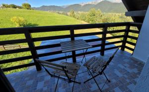two chairs and a table on a balcony with mountains at Vila Pestera in Peştera