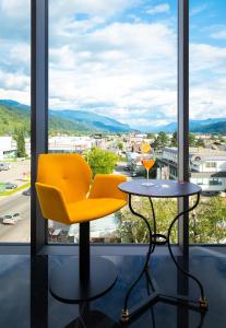 a table and a yellow chair in front of a window at SleepWell24 in Spittal an der Drau