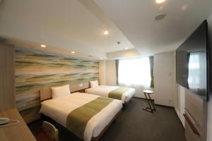 two beds in a hotel room with a painting at Kuretake Inn Premium Numazu Kitaguchi Ekimae in Numazu