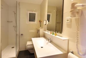 La salle de bains blanche est pourvue d'un lavabo et d'une douche. dans l'établissement Aparthotel Solifemar, à Castelldefels