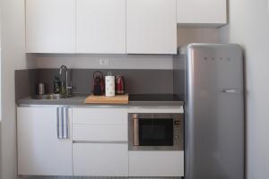 eine Küche mit weißen Schränken und einem Kühlschrank aus Edelstahl in der Unterkunft BnButler - Aquileia - Bilocale a Due Passi da Navigli e Museo Scienza in Mailand