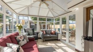 a conservatory with a couch and chairs and windows at Lake Retreat in Poole