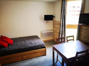 a bedroom with a bed and a table and a window at Borsat - Beau Studio 4pax sur les pistes, avec balcon in Tignes