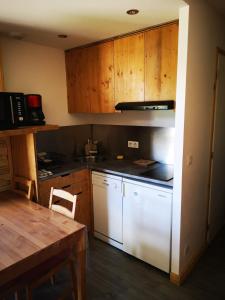 a kitchen with white appliances and a wooden table at Borsat - Beau Studio 4pax sur les pistes, avec balcon in Tignes