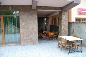 un patio con mesa, sillas y pared de piedra. en Vila Silvia, en Eforie Sud