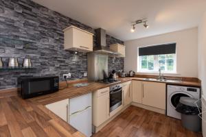 a kitchen with white cabinets and a stone wall at Park View in Billingham