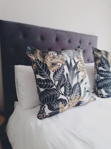 a bed with pillows on it with a black headboard at Ons Strandhuisie Mh18 in Pearly Beach in Pearly Beach