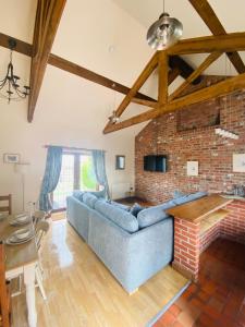 a living room with a blue couch and a brick wall at Field Farm Holiday Cottages and Glamping in Anderby
