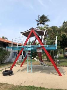 um parque infantil com uma estrutura de brincar em frente a uma casa em Flat Bangalô 103 em Cabo Frio