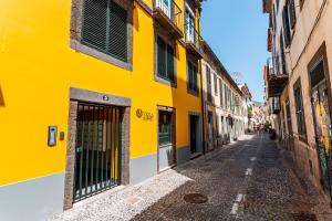 um edifício amarelo numa rua num beco em FLH Viola Market Flats no Funchal