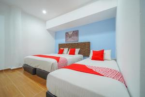 two beds in a hotel room with red pillows at JMA FERRINGHI BEACH HOTEL in Batu Ferringhi