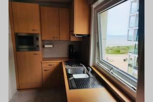 een kleine keuken met een wastafel en een raam bij Zeedijk appartement Nieuwpoort in Nieuwpoort