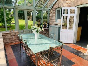 a glass conservatory with a table and chairs on a patio at Beautiful Old Water Mill in Rural Herefordshire in Hereford