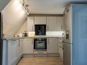 a kitchen with white cabinets and a refrigerator at Pass the Keys Renovated Apartment in the Centre of Canterbury in Canterbury