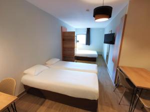 a small room with two beds and a table and a desk at Apparthotel Torcy in Torcy