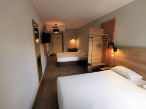 a hotel room with two beds and a mirror at Apparthotel Torcy in Torcy