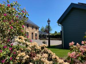 una casa con fiori rosa in un cortile di B&B Ferienhof AB Wellness Suite a Bullange/Büllingen