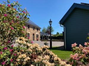 ein Haus mit rosa Blumen im Hof in der Unterkunft B&B Ferienhof AB Wellness Suite in Büllingen