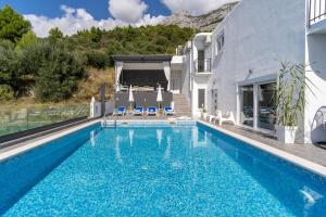 a swimming pool with blue water in front of a building at NEW! Villa Lea 5-bedroom villa with private pool and amazing views of city and sea in Makarska