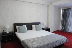 um quarto com uma grande cama branca com duas mesas de cabeceira em Hotel Corona em Drobeta-Turnu Severin