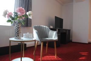 Cette chambre dispose d'une chaise et d'une table avec un vase de fleurs. dans l'établissement Hotel Corona, à Drobeta-Turnu Severin