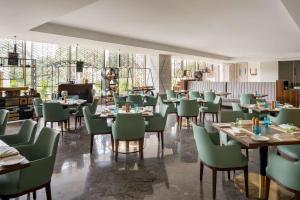 uma sala de jantar com mesas e cadeiras verdes em Radisson Bhopal em Bhopal