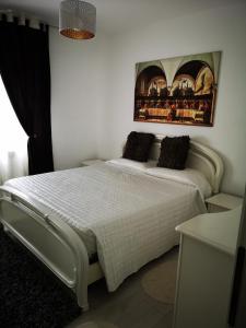 Un dormitorio con una cama blanca con una foto en la pared en Apartament Darius, en Târgu Ocna