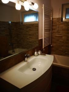 y baño con lavabo, espejo y bañera. en Apartament Darius, en Târgu Ocna