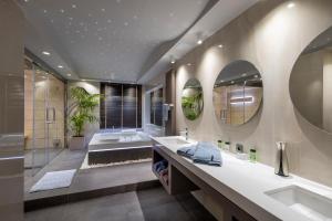 a bathroom with two sinks and a tub and mirrors at Iakovakis Suites & Spa in Koropi
