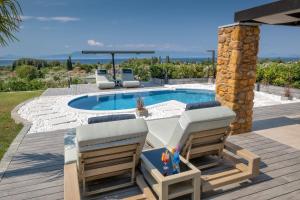 a patio with two chairs and a swimming pool at Iakovakis Suites & Spa in Koropi