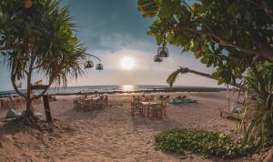 una playa con mesas y sillas y el océano en The Lazy Lodge en Ko Lanta