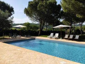a swimming pool with chairs and umbrellas at Agriturismo Sotto il Colle in Assisi