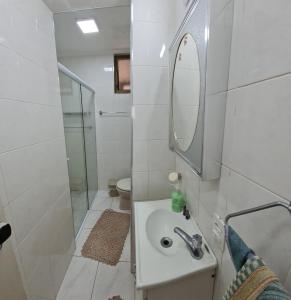 une salle de bain blanche avec un lavabo et un miroir dans l'établissement Ap da Mama, à Guarujá 28 autres photos