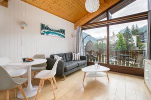 een woonkamer met een bank en een tafel en stoelen bij Stunning renovated studio with mezzanine in Morzine