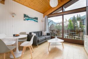 a living room with a couch and a table and chairs at Stunning renovated studio with mezzanine in Morzine