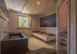 baño con bañera grande y ventana en Ciasa Iachin Mountain Apartment en San Martino in Badia