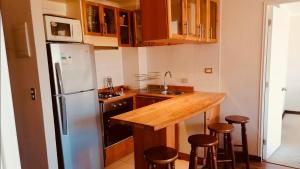 a kitchen with a refrigerator and a counter with stools at Depto Pucon WIFI Internet full equipado a 2 min de lago y centro in Pucón