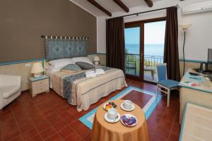 a bedroom with a bed and a balcony with the ocean at Baga Baga in Castelsardo