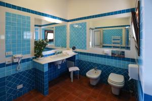 bagno piastrellato blu con servizi igienici e lavandino di Baga Baga a Castelsardo