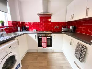 uma cozinha com armários brancos e uma parede de tijolos vermelhos em Glasgow 2bd City Centre Apartment - Free Private Parking em Glasgow