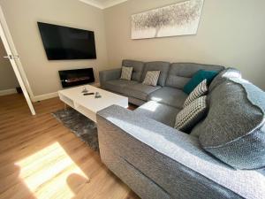 uma sala de estar com um sofá cinzento e uma mesa em Glasgow 2bd City Centre Apartment - Free Private Parking em Glasgow
