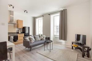 a living room with a couch and a tv at Modern & bright 1 bed for 4 close to city centre! in Edinburgh