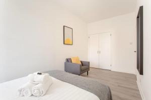 a white bedroom with a bed and a chair at Modern & bright 1 bed for 4 close to city centre! in Edinburgh +44 photos