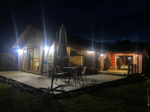 una casa con terraza de madera por la noche en El Reflejo Lodge Spa - Queilen - Chiloé, en Queilén