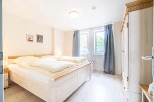 a bedroom with a white bed and a window at Nordland Appartements Wohnung Fünen in Wyk auf Föhr +13 photos
