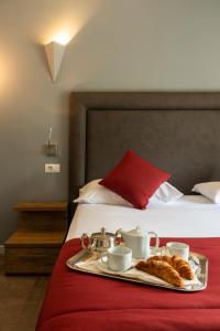 un vassoio di croissant e tazze su un letto di Hotel Ristorante La Quartina a Mergozzo