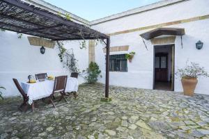 un patio con mesa y sillas y un edificio en casa rural el niño Santamaría , con piscina y wifi en Vejer de la Frontera