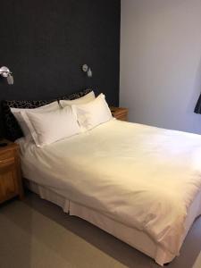 1 cama grande con sábanas y almohadas blancas en Rutland Rooms, en Oakham