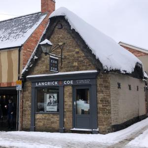 un bâtiment en briques avec de la neige sur le toit dans l'établissement Rutland Rooms, à Oakham