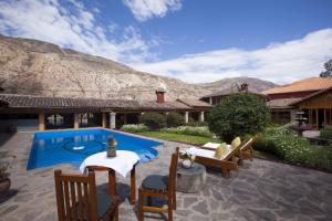 a backyard with a pool and chairs and a house at Hotel San Agustin Urubamba in Urubamba